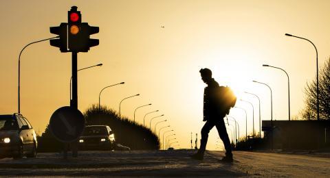 Maður gengur yfir Suðurgötu með sólina bak við sig